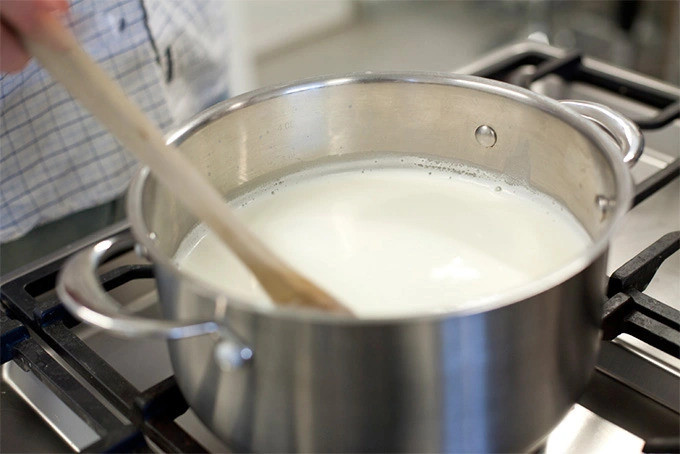 Vừa đun sữa ở lửa nhỏ vừa liên tục khuấy để duy trì sữa ở mức ổn định 
